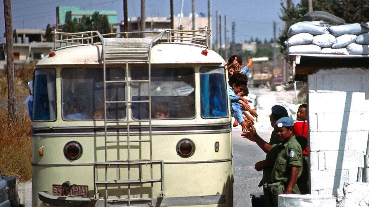 Children reach out to peacekeepers from inside of a vehicle.