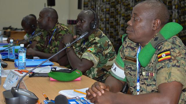 Men in uniform sit at a table in front of microphones