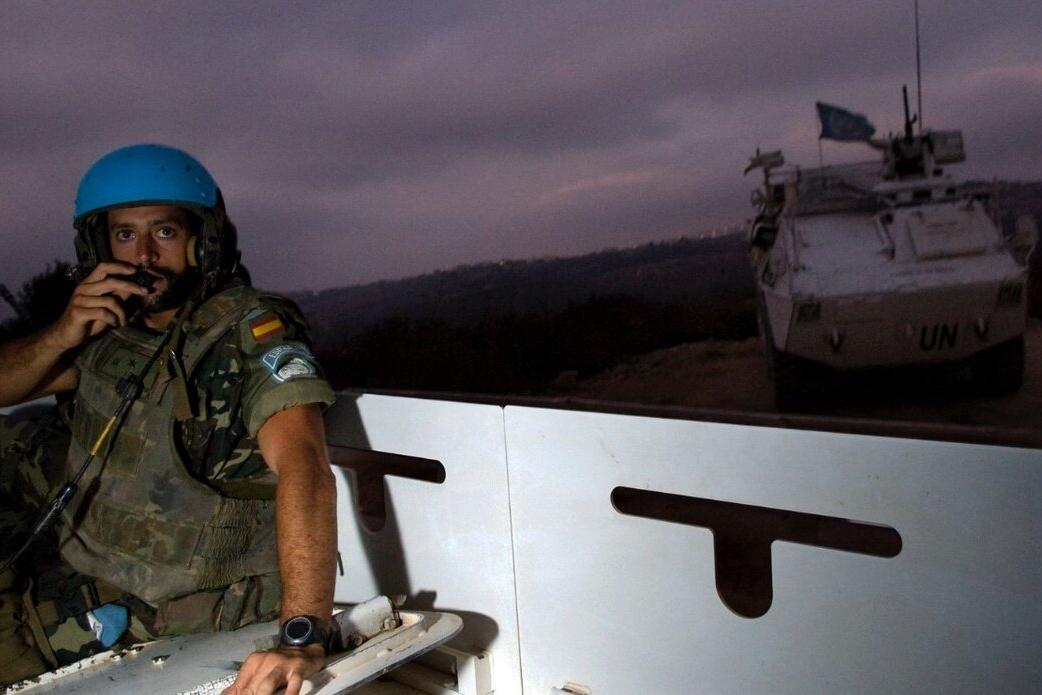 A peacekeeper uses radio equipment on a vehicle outside.